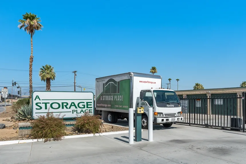 A storage place moving truck near the front gate and sign of a facility.