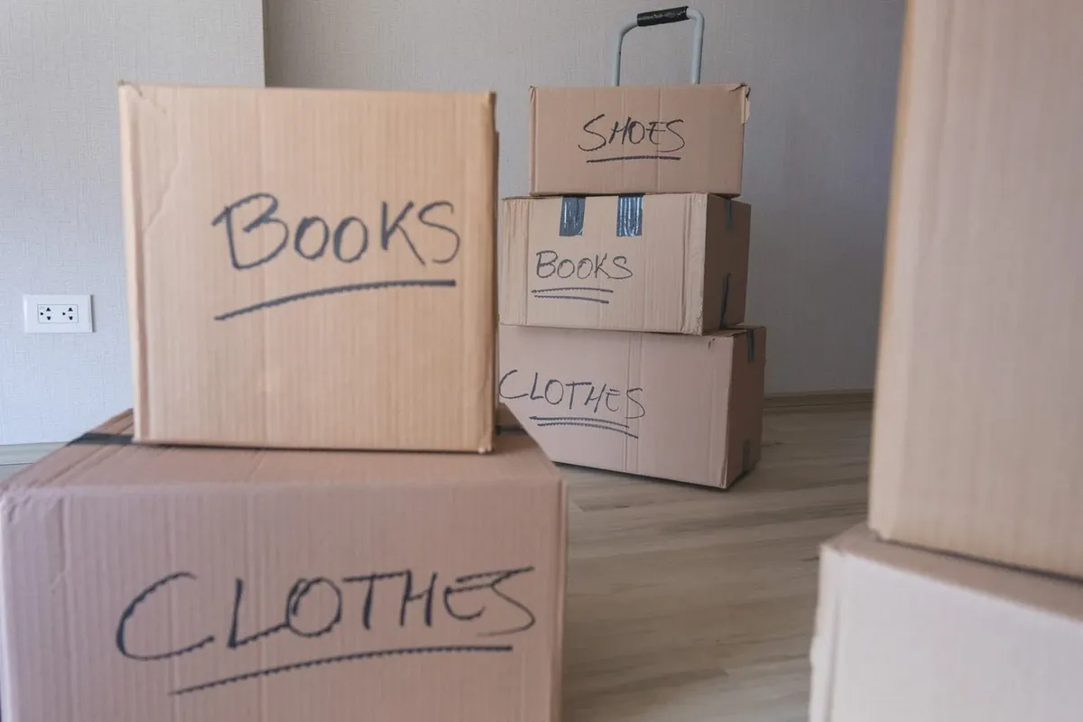A collection of moving boxes for shoes, books, and clothes is stacked for moving.