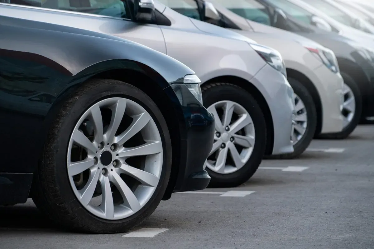 A row of black, white, and grey cars aligned in a car lot.